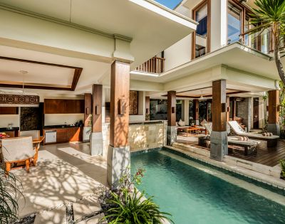 Luxurious open-concept villa with a modern design, featuring a stylish living area, lush pool, wooden accents, and tropical plants, creating a serene atmosphere.