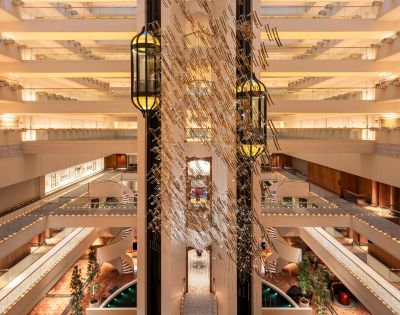 Spacious hotel atrium with multiple floors, modern decor, glass elevators, and warm lighting. Symmetrical design evokes elegance and grandeur.