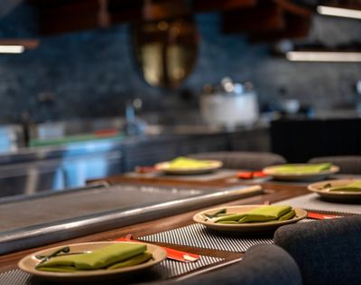 A sleek, modern kitchen setup with a row of elegant place settings, featuring green napkins and red chopsticks, creates a welcoming dining atmosphere.