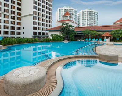 Luxurious outdoor pool scene with clear, blue water surrounded by elegant, tall buildings and lush greenery, evoking a tranquil and relaxing atmosphere.
