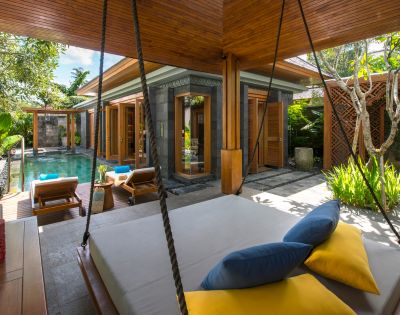 Luxurious tropical villa with a private pool, surrounded by lush greenery. Features a cozy outdoor swing bed with blue and yellow cushions, exuding relaxation.