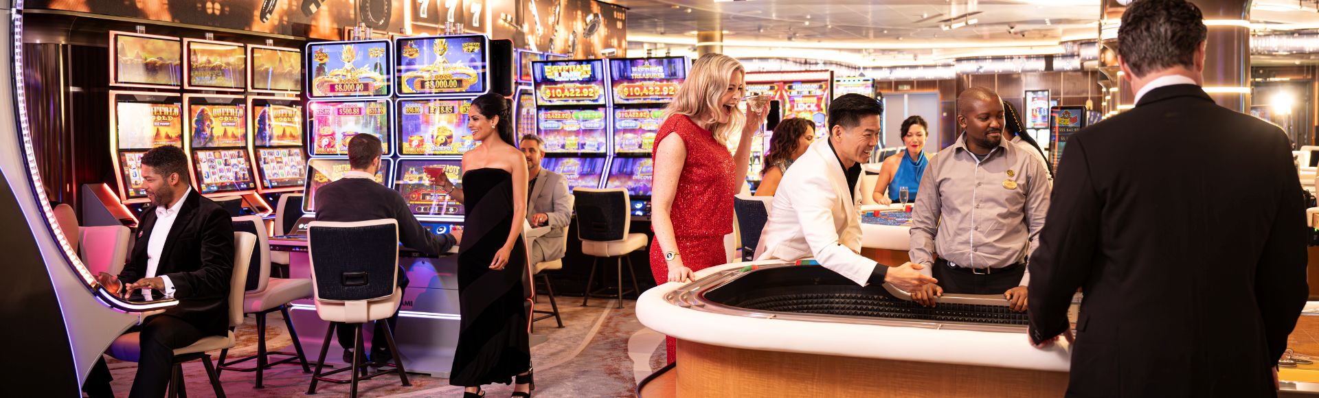 People dressed formally playing slot machines and table games inside a brightly lit casino.