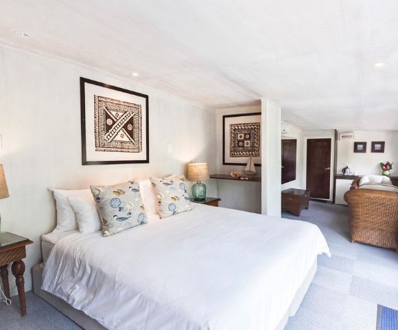Bright, elegant bedroom with a large bed adorned with patterned pillows. Two framed artworks hang on white walls. Warm lighting from bedside lamps adds coziness.