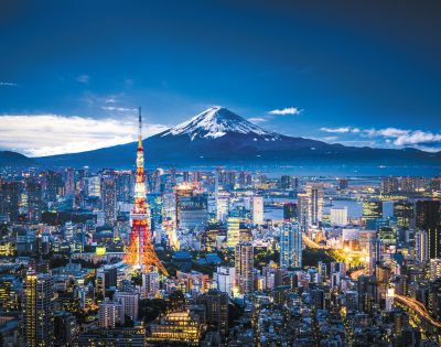 Tokyo cityscape at dusk with Mount Fuji in the background. The Tokyo Tower is brightly illuminated, contrasting against the vibrant sky and urban lights.