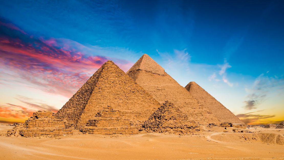 Ancient pyramids under a vibrant sky blend with the desert landscape, conveying a sense of timeless grandeur and mystery.