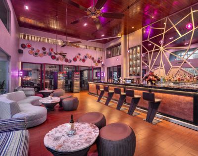 Modern bar interior with warm lighting, sleek black stools along a stylish counter. Cozy seating, artistic wall decor, and a relaxed, inviting atmosphere.