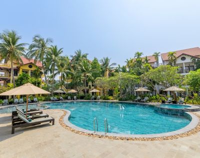 Tropical resort pool surrounded by palm trees and lounge chairs with umbrellas. Bright and sunny, conveying a relaxed and inviting atmosphere.