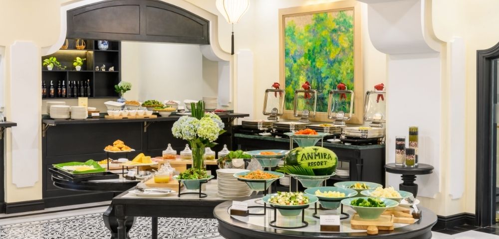 Buffet setup with various dishes, salads, and a carved watermelon labeled 