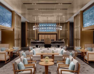 A luxurious hotel lobby with modern seating arrangements, a grand reception desk, and large abstract blue paintings on the walls.