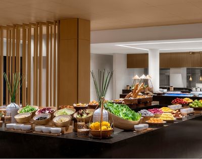 Buffet table laden with various fresh fruits, salads, and breads in a well-lit dining area.