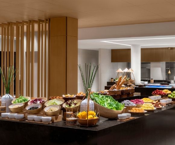 Buffet table laden with various fresh fruits, salads, and breads in a well-lit dining area.