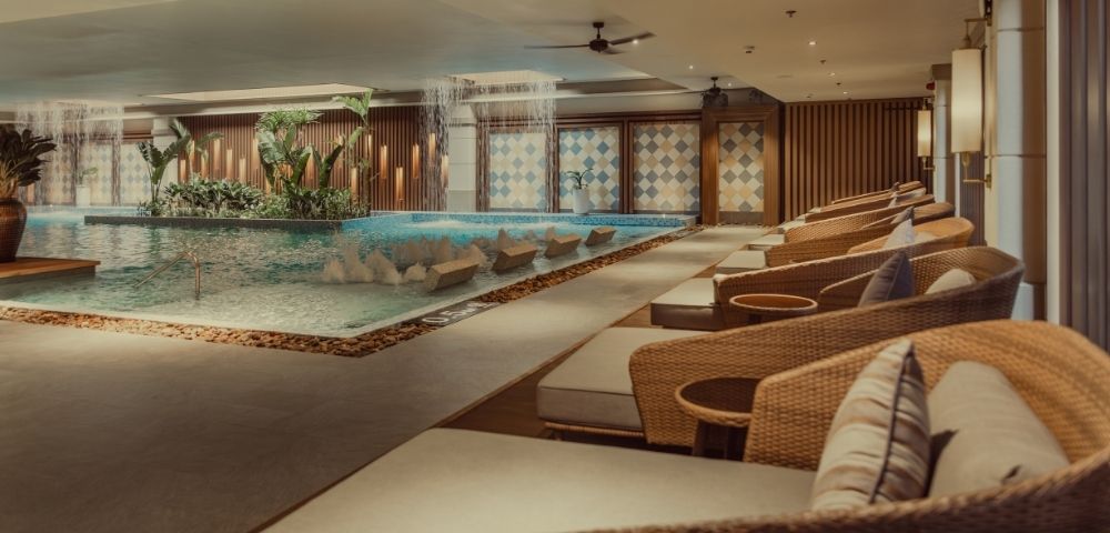 An indoor spa area featuring a serene pool, comfortable lounge chairs, and decorative lighting.