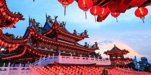 Traditional Chinese temple adorned with numerous red lanterns glowing warmly at dusk, intricate roof designs, vibrant festive ambiance.