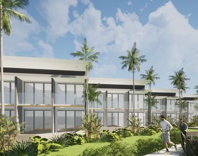 A modern, multi-story building with large windows and balconies is surrounded by lush tropical foliage and palm trees, with two people jogging on a path in the foreground under a cloudy blue sky.
