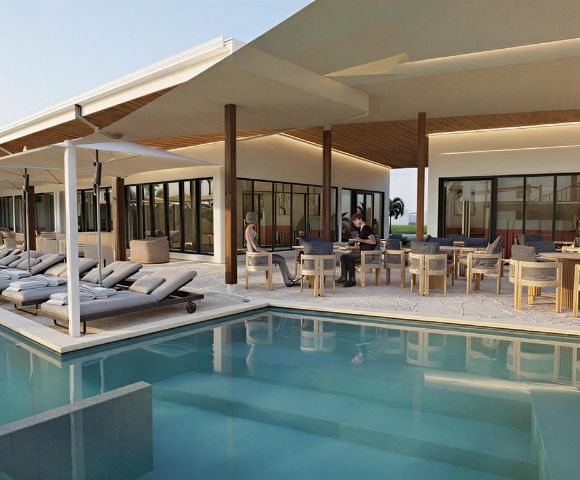A modern resort pool area with lounge chairs and an outdoor dining patio.