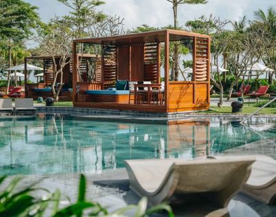 Wooden pavilion structure over a pool area with seating and shaded relaxation space