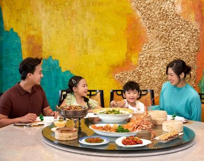 Group of people sharing a meal at a round table filled with various dishes