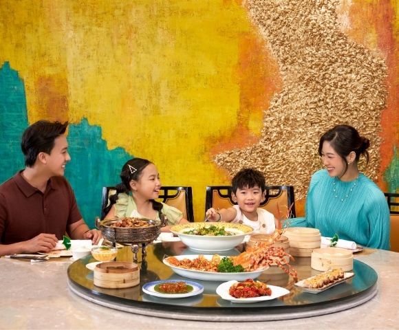 Group of people sharing a meal at a round table filled with various dishes