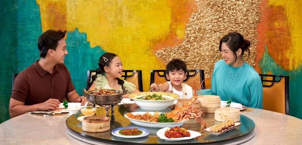 Group of people sharing a meal at a round table filled with various dishes