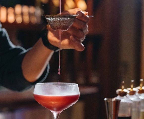 Close-up of a cocktail glass being held at a bar with warm ambient lighting
