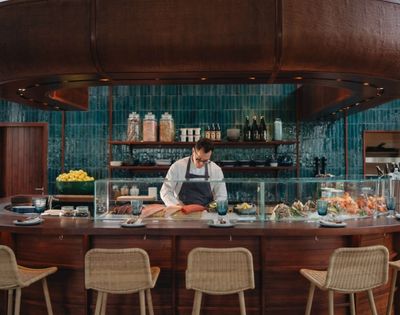 Sushi bar with chef preparing food behind a counter with stools in front