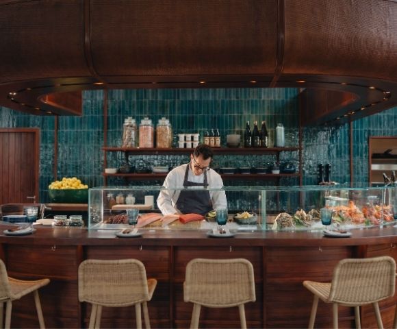 Sushi bar with chef preparing food behind a counter with stools in front