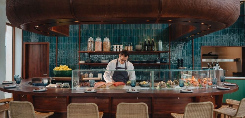 Sushi bar with chef preparing food behind a counter with stools in front