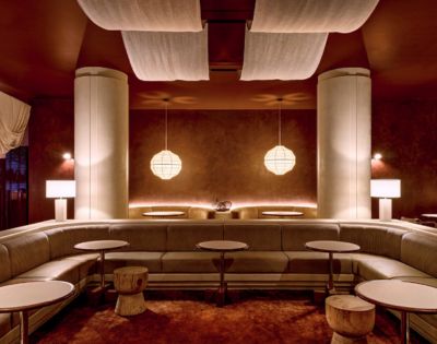 A modern lounge area with a curved sofa, round tables, and minimalist pendant lights.