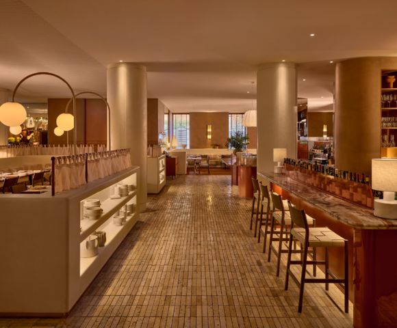 An elegant restaurant interior with a marble bar, seating, and dining areas.