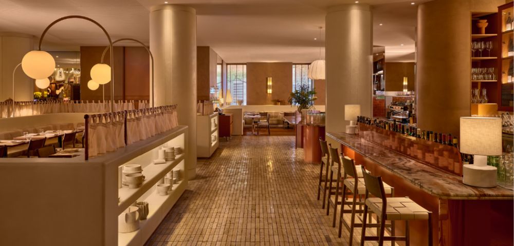 An elegant restaurant interior with a marble bar, seating, and dining areas.