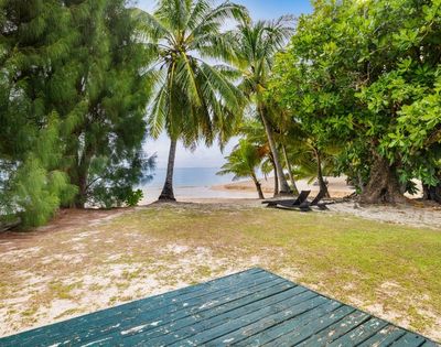 Sandy beachfront area shaded by tropical trees with ocean views beyond