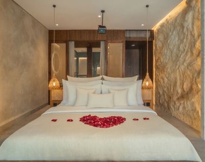 Elegant bedroom with a king-size bed, textured stone walls, and soft ambient lighting