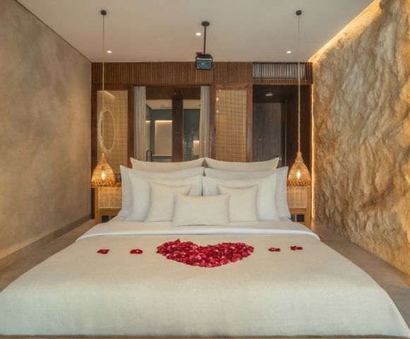 Elegant bedroom with a king-size bed, textured stone walls, and soft ambient lighting
