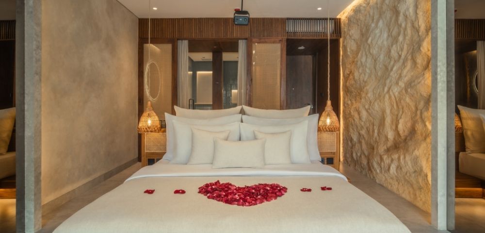 Elegant bedroom with a king-size bed, textured stone walls, and soft ambient lighting