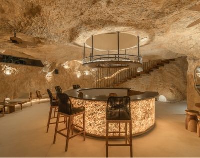 Elegant bedroom with a king-size bed, textured stone walls, and soft ambient lighting