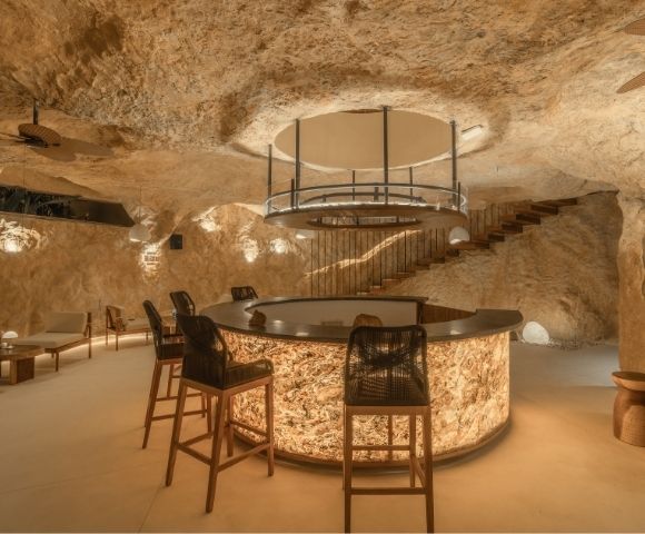 Elegant bedroom with a king-size bed, textured stone walls, and soft ambient lighting