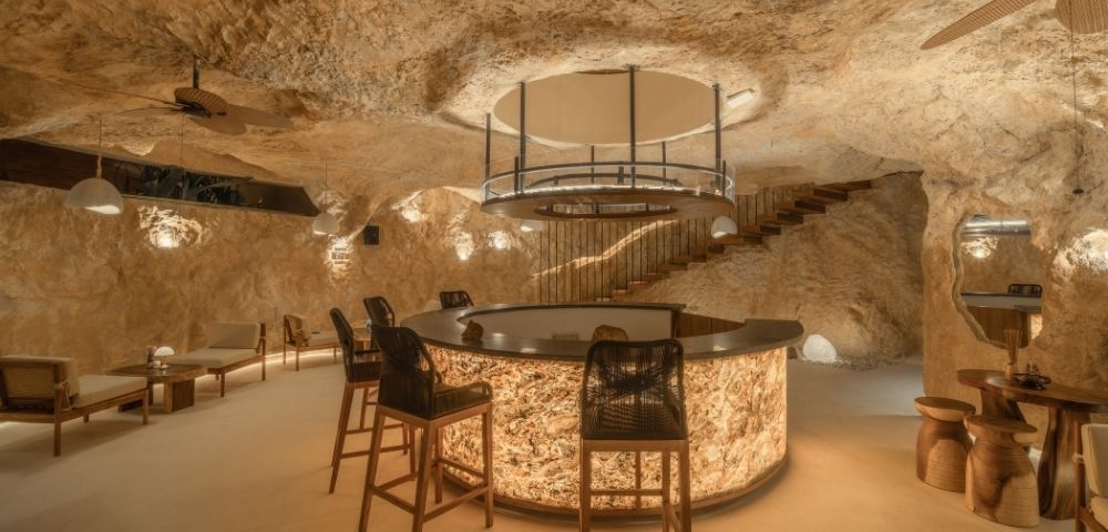 Elegant bedroom with a king-size bed, textured stone walls, and soft ambient lighting