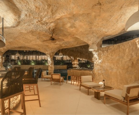 Spacious cave-style lounge featuring seating areas, stone walls, and a relaxed atmosphere
