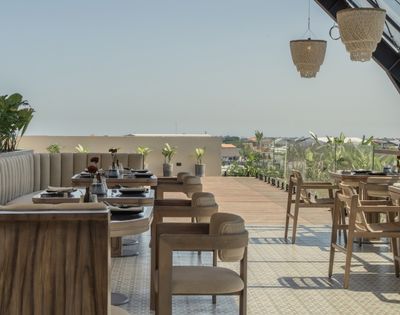 Open-air dining area with wooden tables and chairs overlooking the surrounding landscape