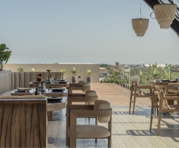 Open-air dining area with wooden tables and chairs overlooking the surrounding landscape