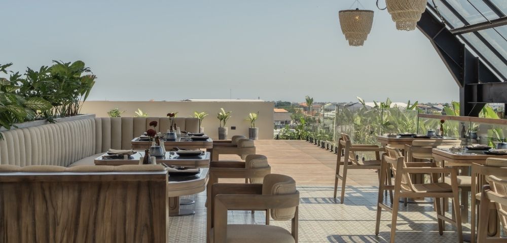 Open-air dining area with wooden tables and chairs overlooking the surrounding landscape