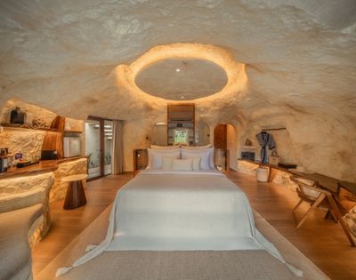 Spacious villa interior with a king-size bed, seating area, and cave-inspired stone design