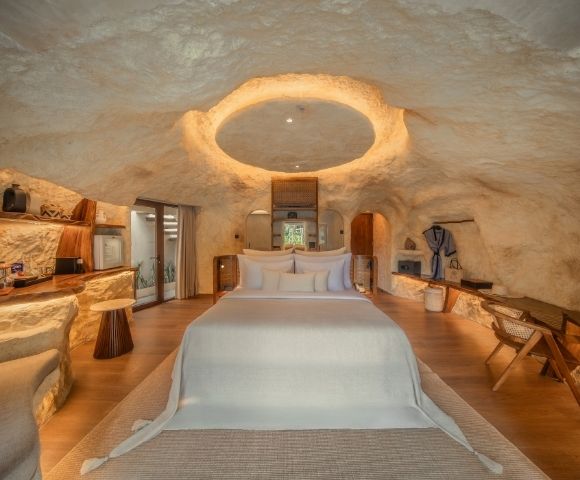 Spacious villa interior with a king-size bed, seating area, and cave-inspired stone design