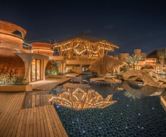 Resort pool illuminated at night with reflections of architectural lighting on the water