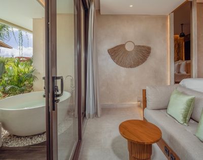 Suite bathroom with a freestanding bathtub overlooking a private pool and garden