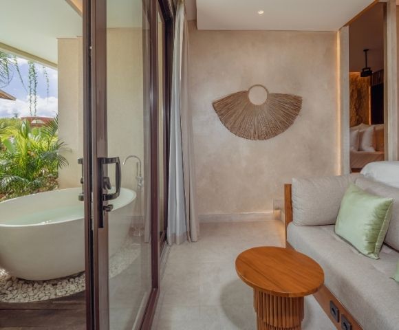 Suite bathroom with a freestanding bathtub overlooking a private pool and garden