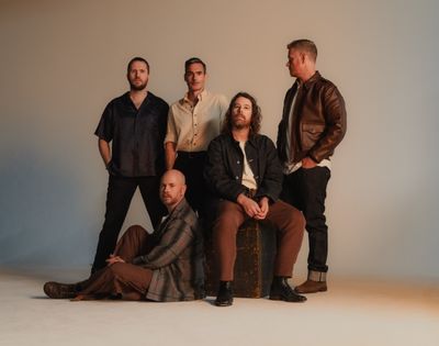 Five men posing for a studio portrait in casual attire.