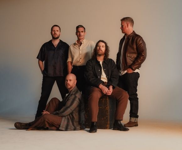 Five men posing for a studio portrait in casual attire.