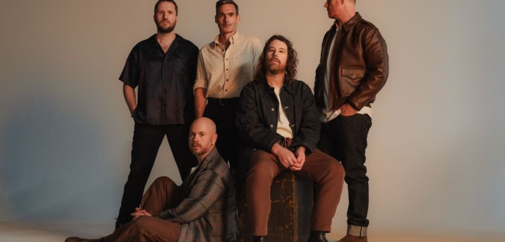 Five men posing for a studio portrait in casual attire.