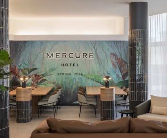 Interior lobby of Mercure Hotel Spring Hill with a lush green jungle mural and modern seating area.